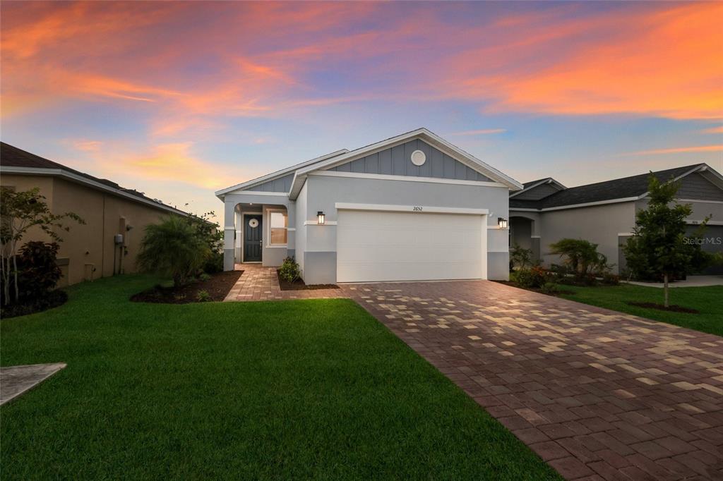 A single-story house with a paved driveway and a two-car garage at sunset — 2652 89TH STREET CIRCLE E, PALMETTO, FL