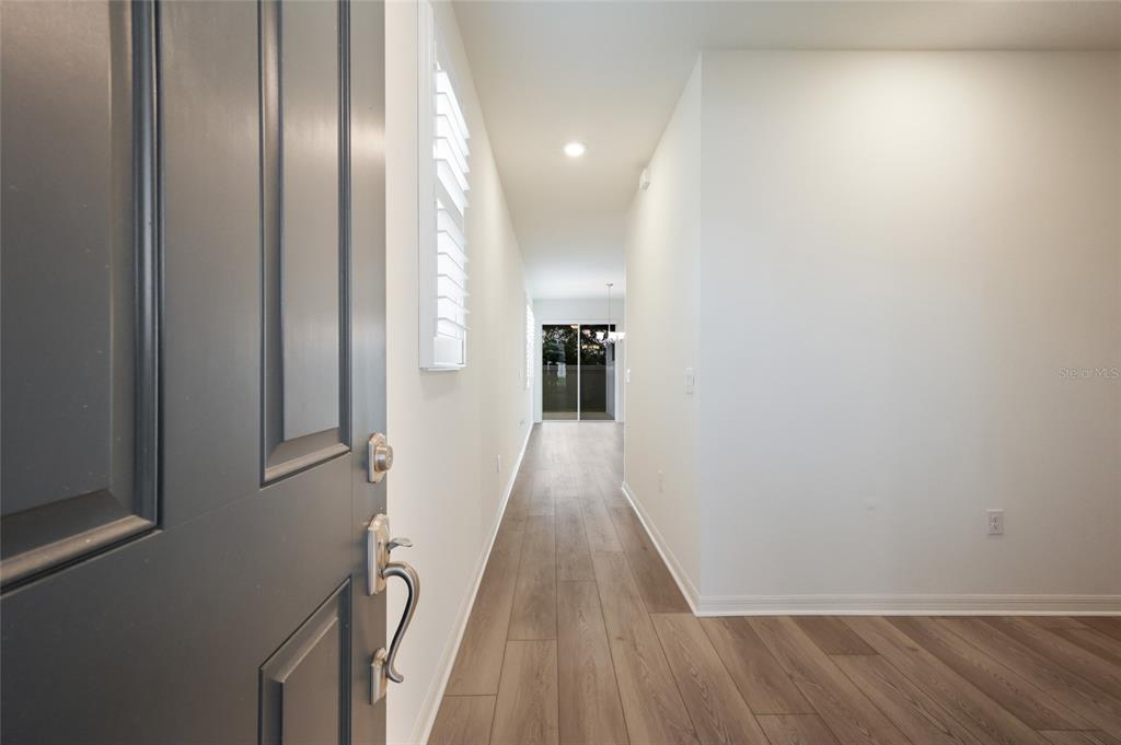 A view from an open front door into a hallway with wood-look flooring — 2652 89TH STREET CIRCLE E, PALMETTO, FL