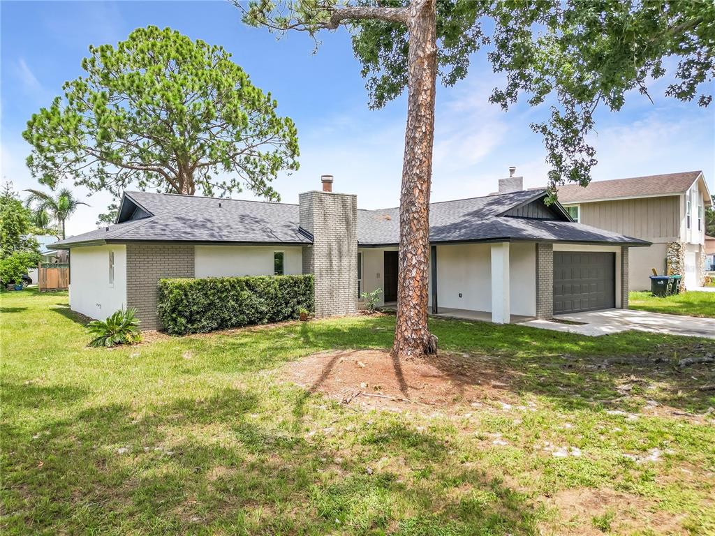 A single-story house with a gray brick chimney, dark roof, and attached garage — 3336 TCU BOULEVARD, ORLANDO, FL