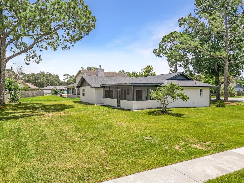 A single-story house with a screened-in porch and a large grassy yard under blue skies — 3336 TCU BOULEVARD, ORLANDO, FL