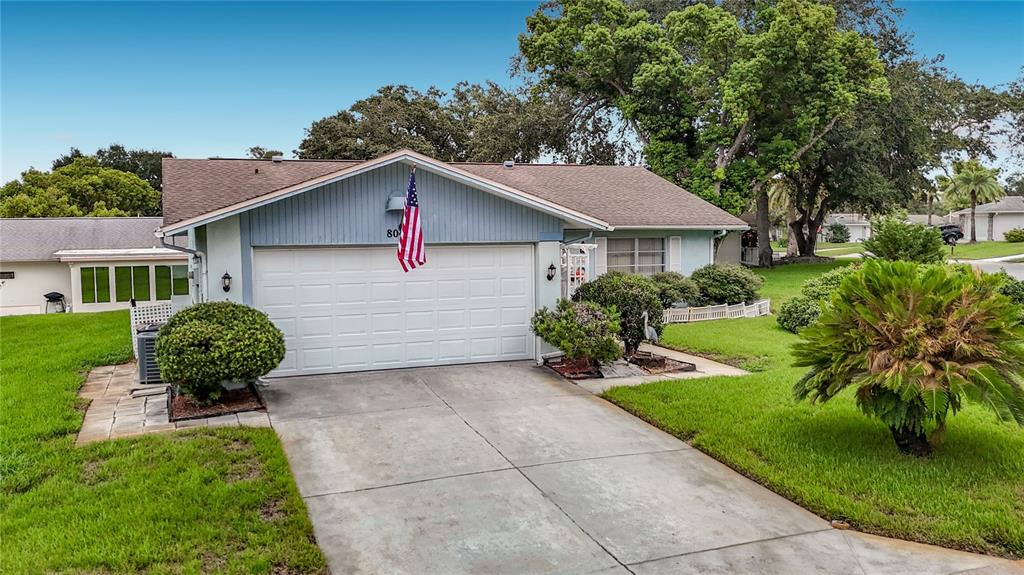 A single-story house with a light blue exterior, a two-car garage, and a concrete driveway — 8045 PASADENA DRIVE, PORT RICHEY, FL