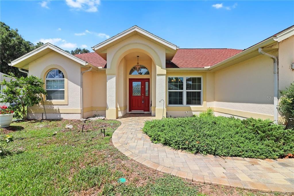 A single-story house with a red front door, arched entryway, and a paved walkway — 3640 E HIDDEN COVE TRAIL, HERNANDO, FL