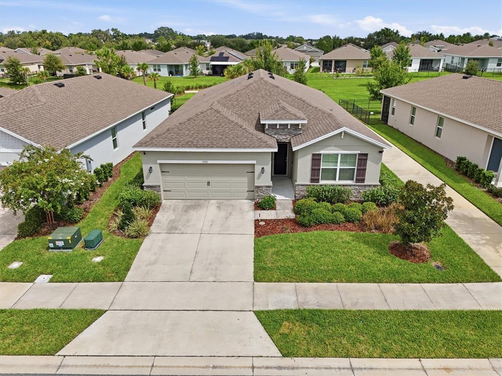 An aerial view shows a single-story house with a two-car garage and a concrete driveway — 5310 SUNSHINE DRIVE, WILDWOOD, FL