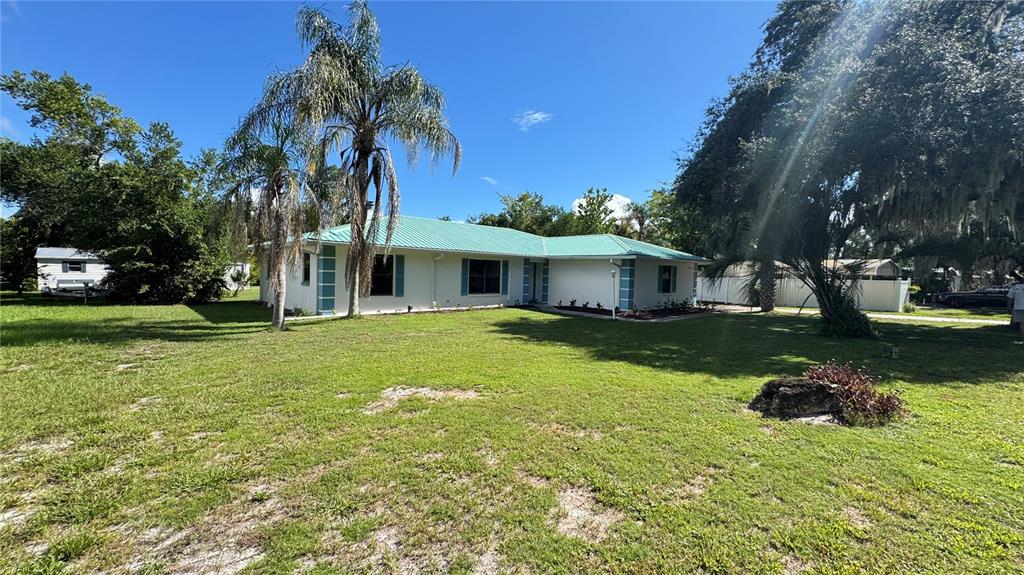 A single-story house with a green metal roof and blue shutters sits on a lawn — 5329 EAGLES NEST ROAD, FRUITLAND PARK, FL
