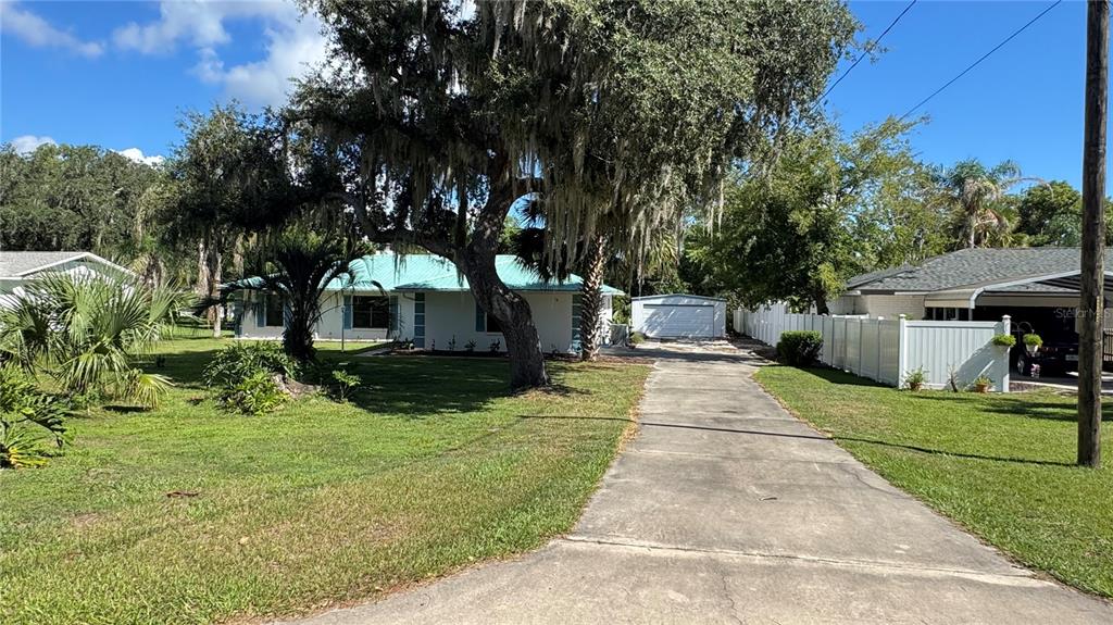 A single-story house with a turquoise roof, a concrete driveway, and a detached garage — 5329 EAGLES NEST ROAD, FRUITLAND PARK, FL