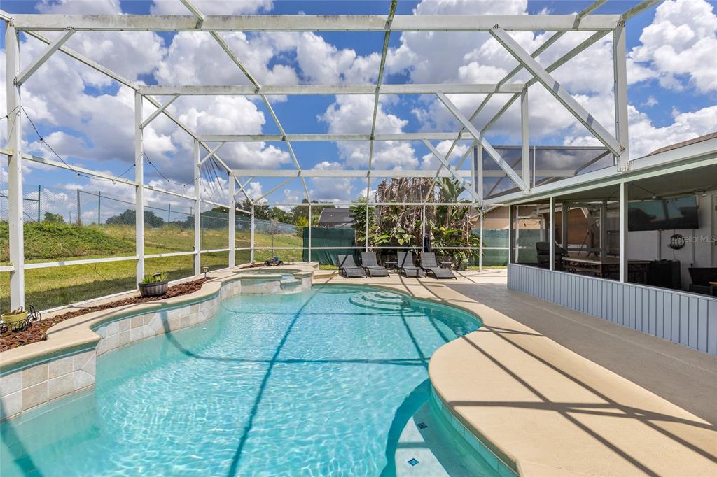 A swimming pool with an attached spa inside a screened-in patio enclosure — 148 VALENTINO COURT, DAVENPORT, FL