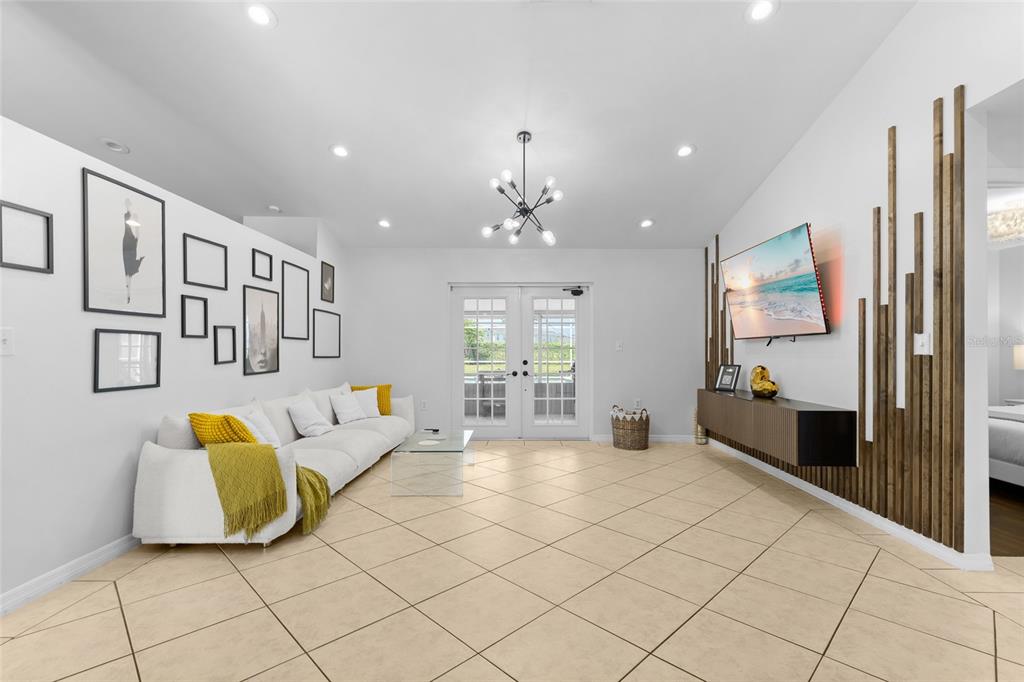 A living room features white walls, a white sofa with yellow accents, and wood slat paneling — 148 VALENTINO COURT, DAVENPORT, FL