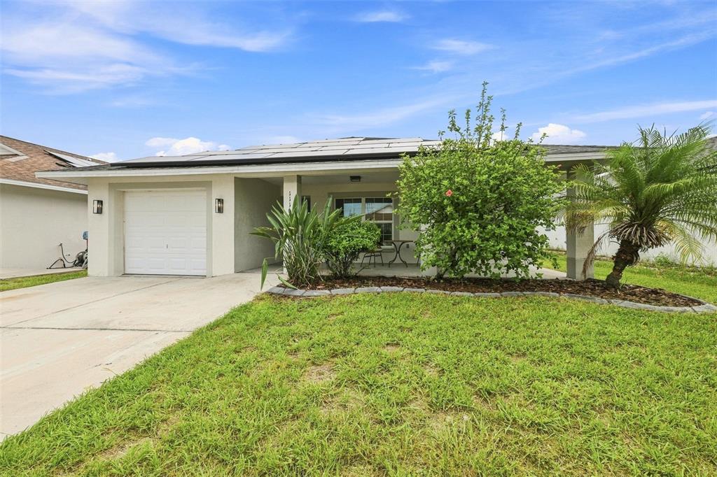 A single-story house with a white garage, covered porch, and solar panels on the roof — 1116 SHARED PASSION STREET, RUSKIN, FL
