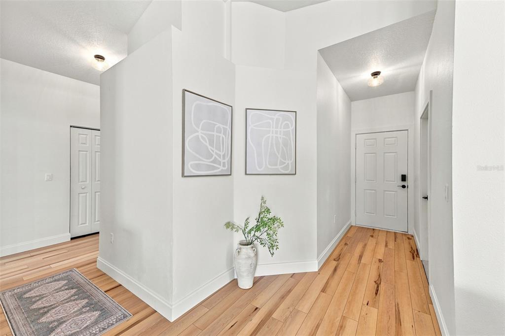 A bright entryway features light wood flooring, white walls, two framed prints, and a vase — 1116 SHARED PASSION STREET, RUSKIN, FL