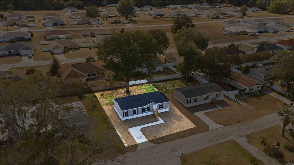 An aerial view shows a single-story manufactured home with a new concrete walkway and driveway — 1560 NE 162ND STREET, CITRA, FL
