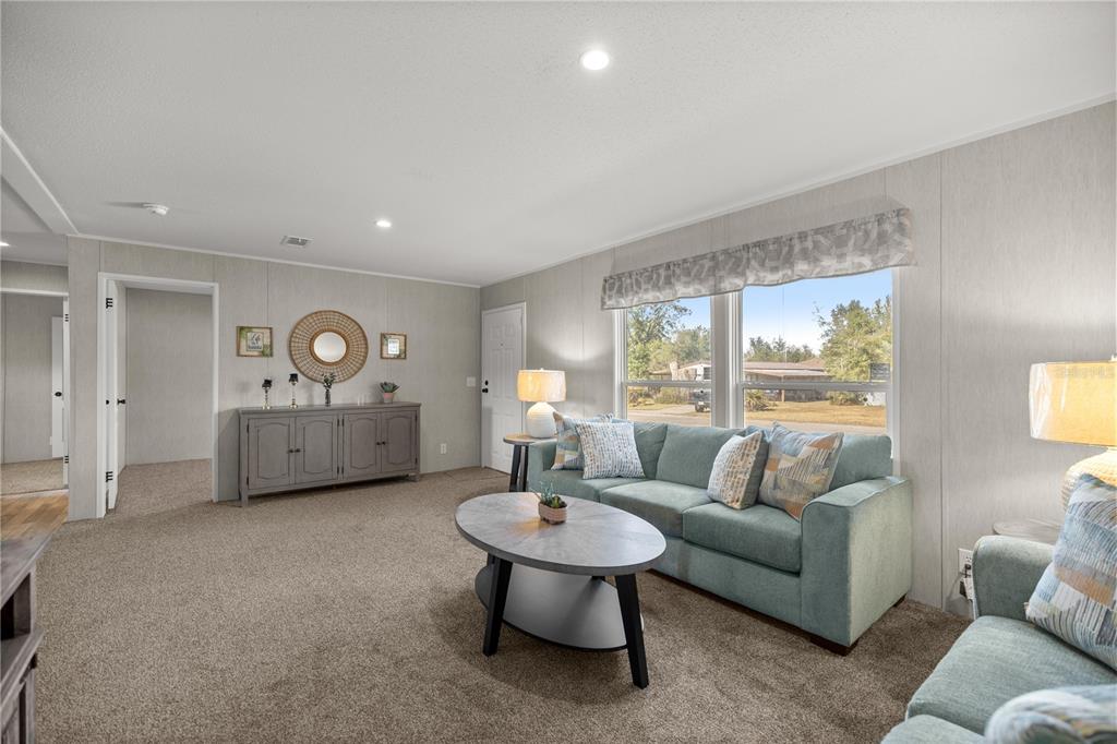 A living room with gray walls, carpeted floors, a teal sofa, and a coffee table — 1560 NE 162ND STREET, CITRA, FL
