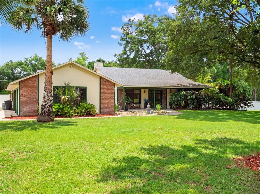 A single-story house with brick accents, a green-trimmed porch, and a large front lawn — 3501 HILL STREAM AVENUE, APOPKA, FL