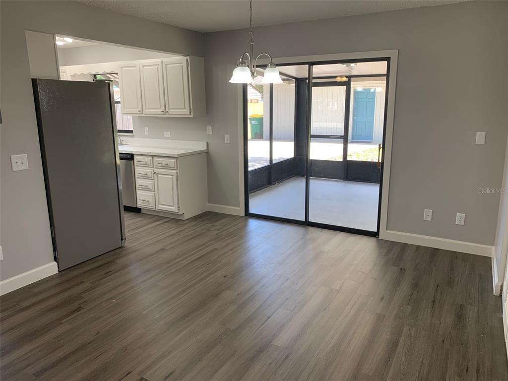 A dining area with wood-look flooring, a stainless steel refrigerator, and a sliding glass door — 527 HILL STREET UNIT A, EUSTIS, FL