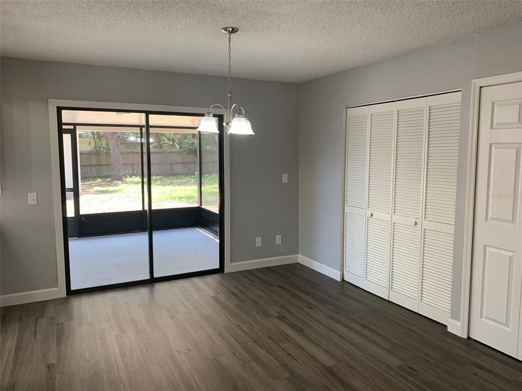 A dining room with gray walls, wood-look flooring, a sliding glass door, and louvered closet doors — 527 HILL STREET UNIT A, EUSTIS, FL
