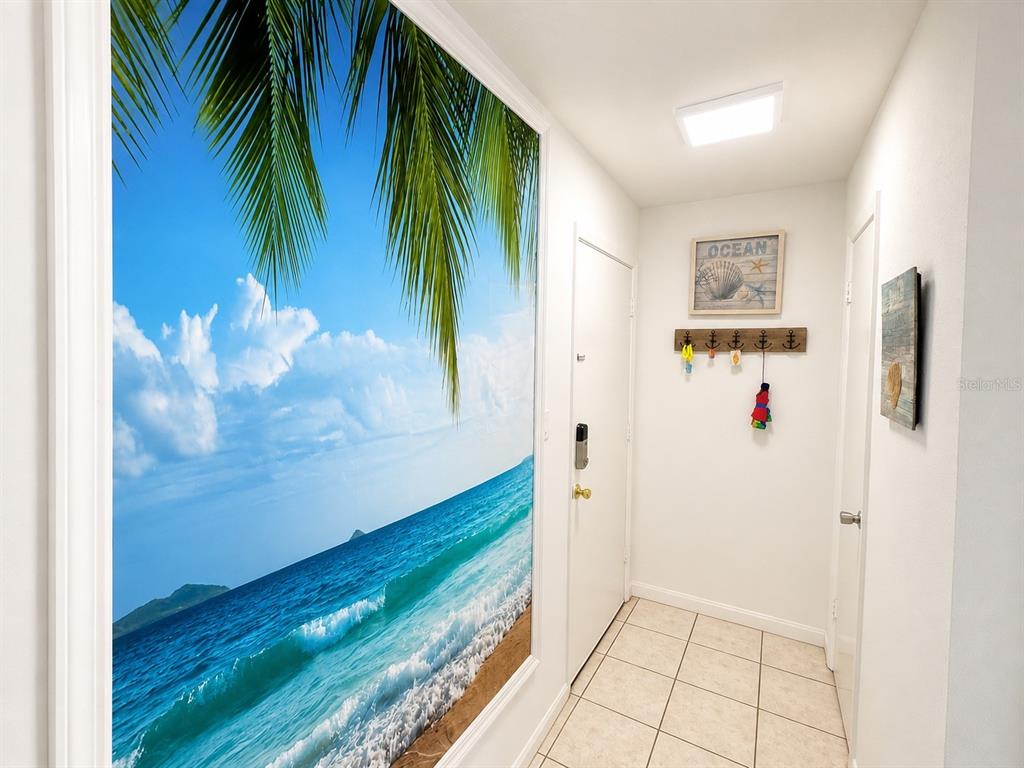 An entryway features a large beach mural, tiled flooring, and a wall-mounted coat rack — 3730 42ND WAY S UNIT H, ST PETERSBURG, FL