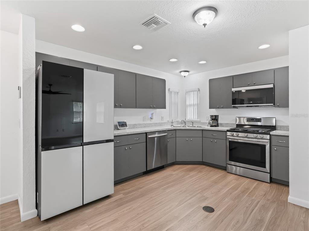 A kitchen features gray cabinets, stainless steel appliances, and light wood-look flooring — 9318 CR 649, BUSHNELL, FL