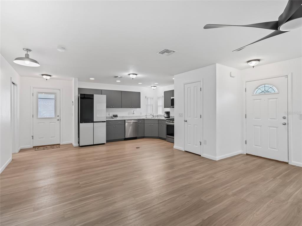 A kitchen with gray cabinets and stainless steel appliances opens into a large living area — 9318 CR 649, BUSHNELL, FL
