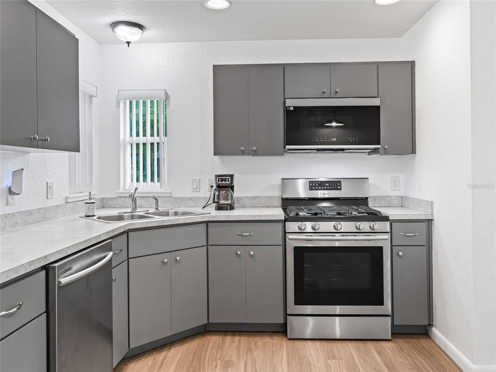 A kitchen features gray cabinets, stainless steel appliances, and light-colored countertops — 9318 CR 649, BUSHNELL, FL