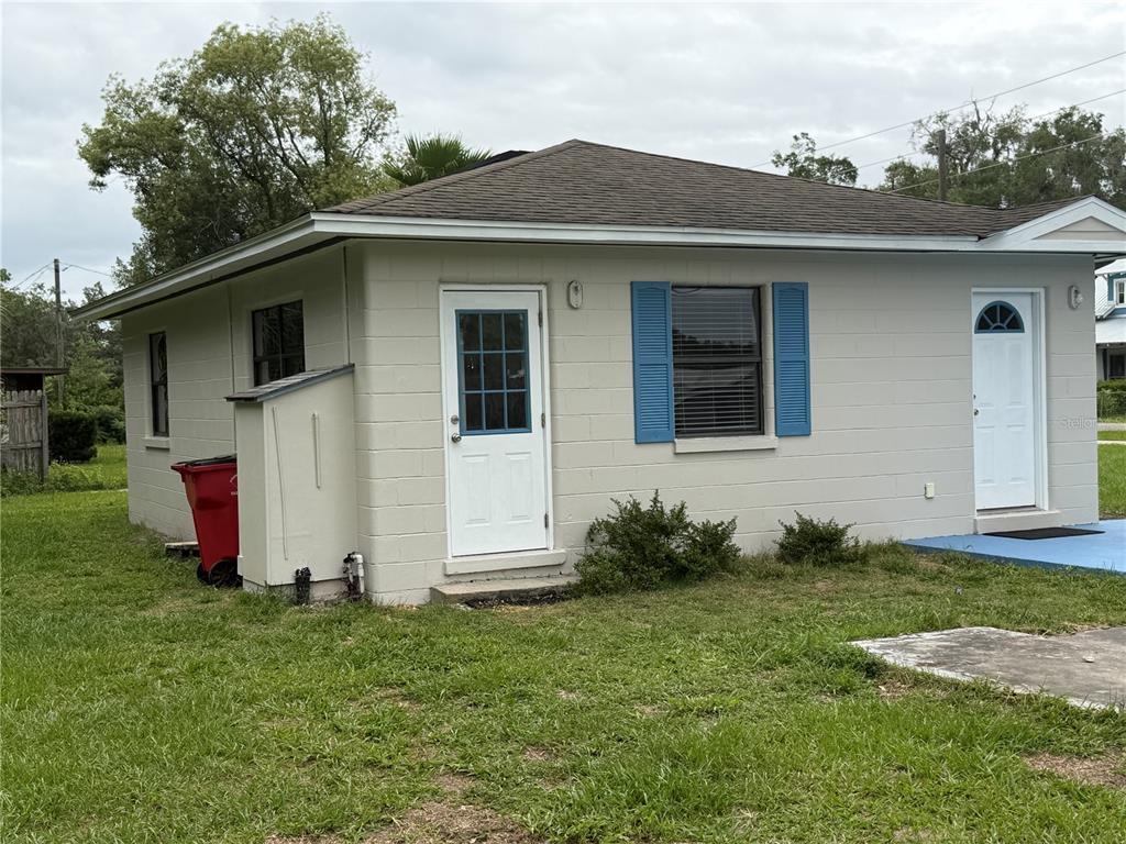 A single-story concrete block house with a white door, blue shutters, and a red trash bin — 2301 E WARM SPRINGS AVENUE, COLEMAN, FL