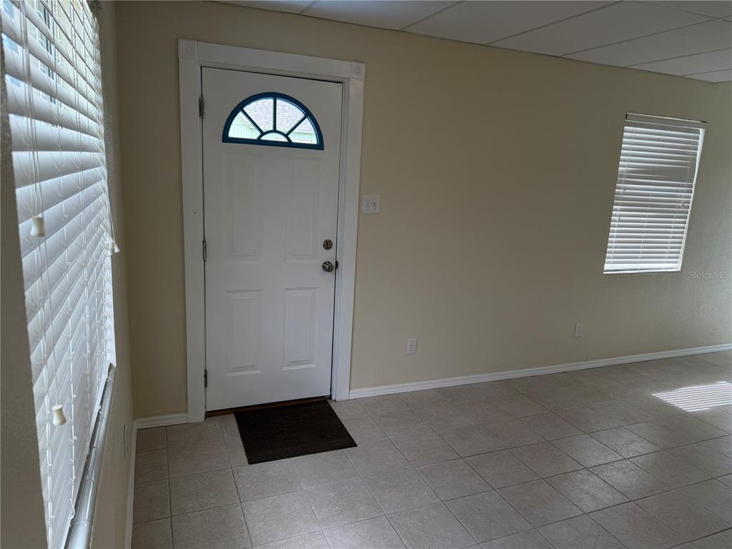 An interior view of a room with tiled floors, a white door, and two windows — 2301 E WARM SPRINGS AVENUE, COLEMAN, FL