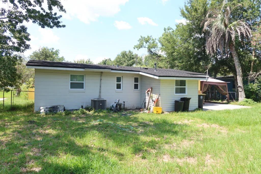 The exterior of a single-story house with light siding, a dark roof, and a backyard — 6731 MOPSY LN, JACKSONVILLE, FL