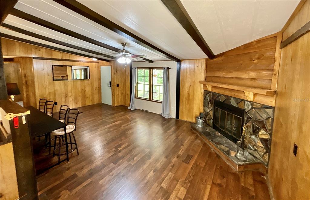 A living room features wood-paneled walls, a stone fireplace, and dark wood-look flooring — 13951 NE 140TH STREET, WALDO, FL