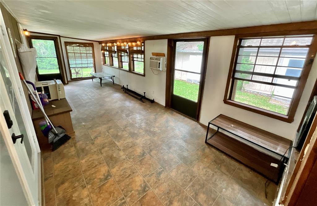 A sunroom features tile flooring, multiple windows, a window air conditioner, and a glass door — 13951 NE 140TH STREET, WALDO, FL