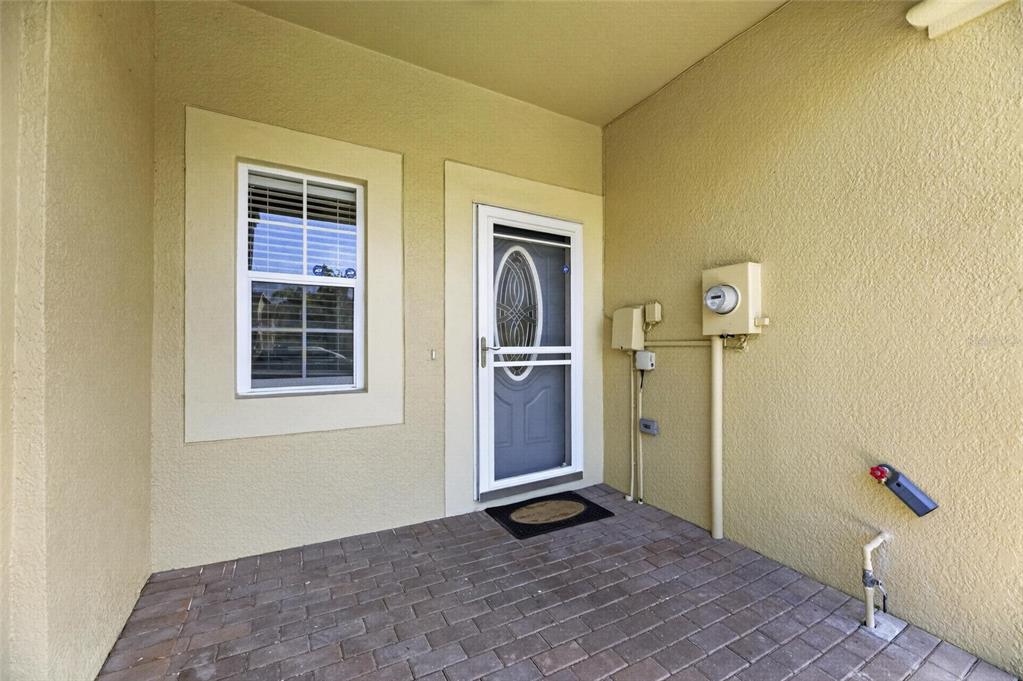 A paved entryway features a front door with a storm door and a single window — 9212 RIVER ROCK LANE, RIVERVIEW, FL