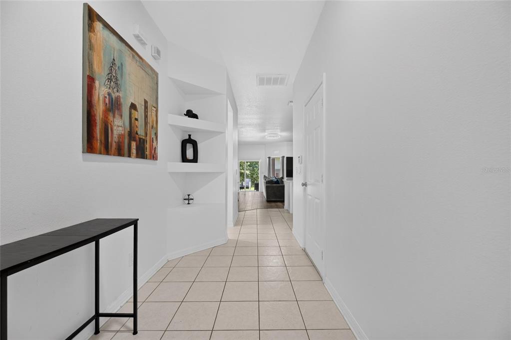A tiled hallway features a built-in display niche, a console table, and wall art — 9212 RIVER ROCK LANE, RIVERVIEW, FL