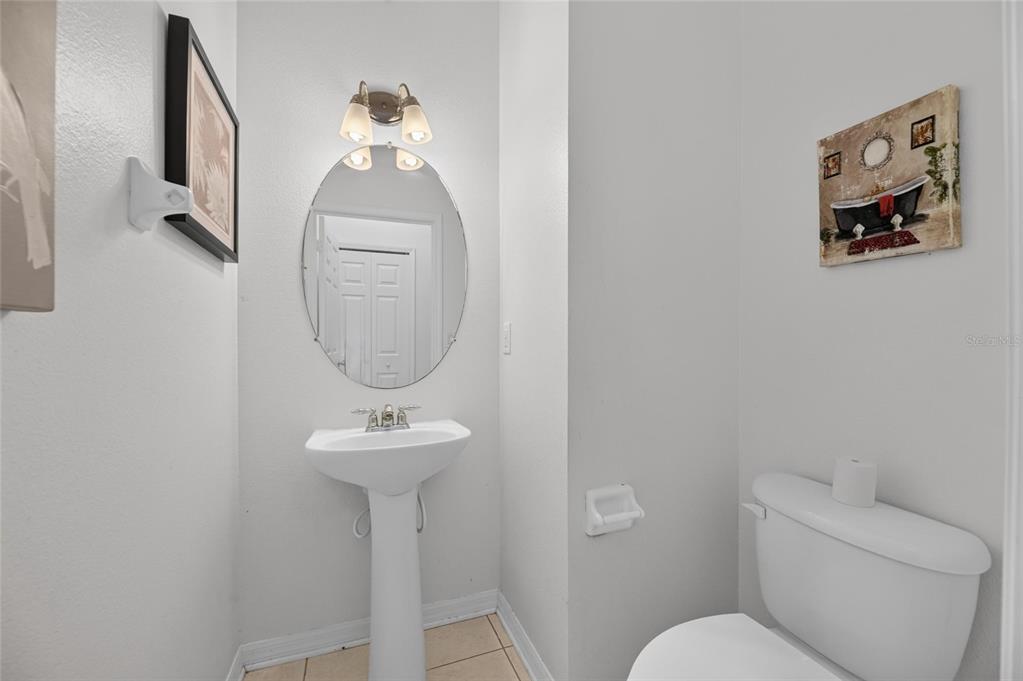A half bathroom features a pedestal sink, oval mirror, wall-mounted light fixture, and a toilet — 9212 RIVER ROCK LANE, RIVERVIEW, FL