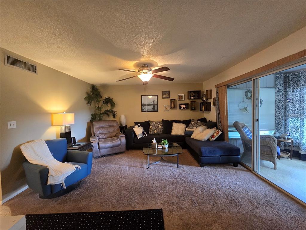 A living room features a blue armchair, a brown recliner, and a dark sectional sofa — 608 MIDWAY DRIVE UNIT A, OCALA, FL