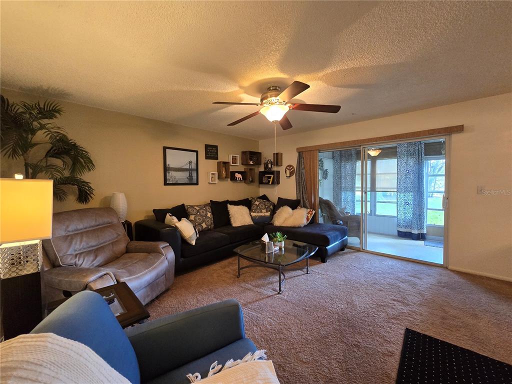A living room features a sectional sofa, a recliner, a ceiling fan, and sliding glass doors — 608 MIDWAY DRIVE UNIT A, OCALA, FL