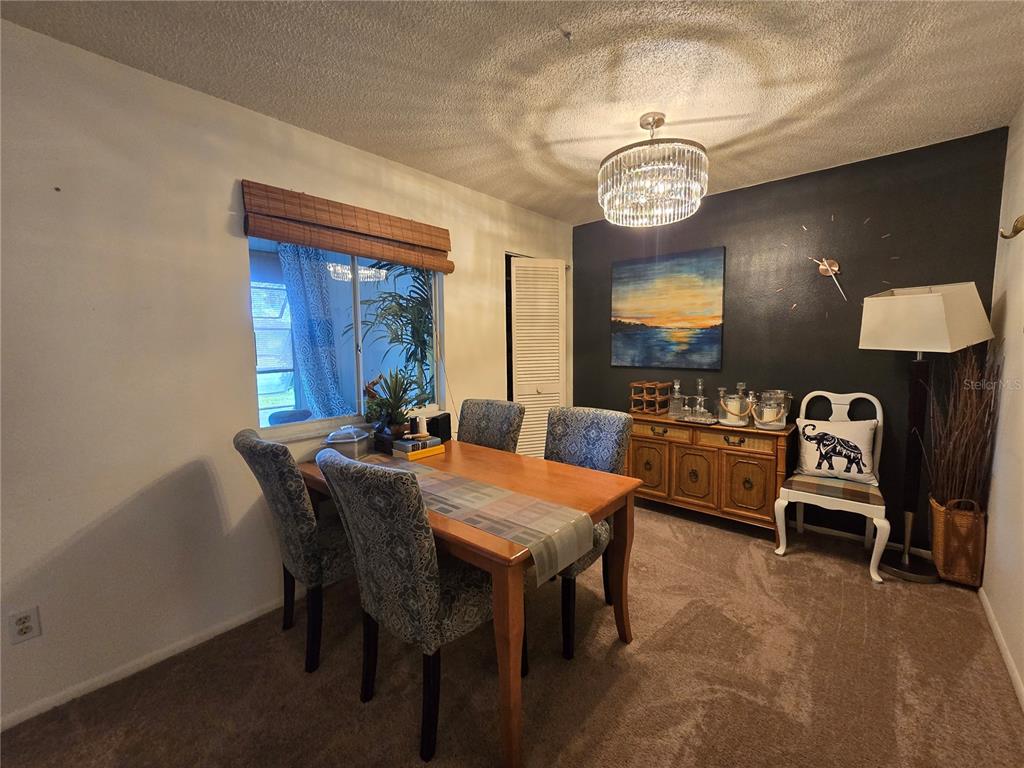 A dining room features a wooden table, patterned chairs, a sideboard, and a crystal chandelier — 608 MIDWAY DRIVE UNIT A, OCALA, FL