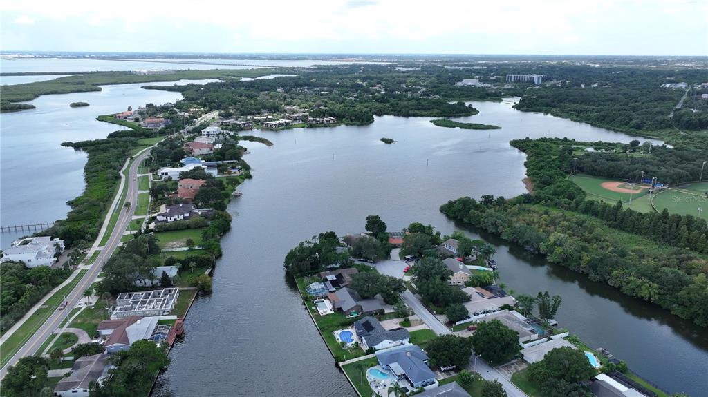 An aerial view shows waterfront homes along a canal leading to a large bay — 560 7TH STREET S, SAFETY HARBOR, FL