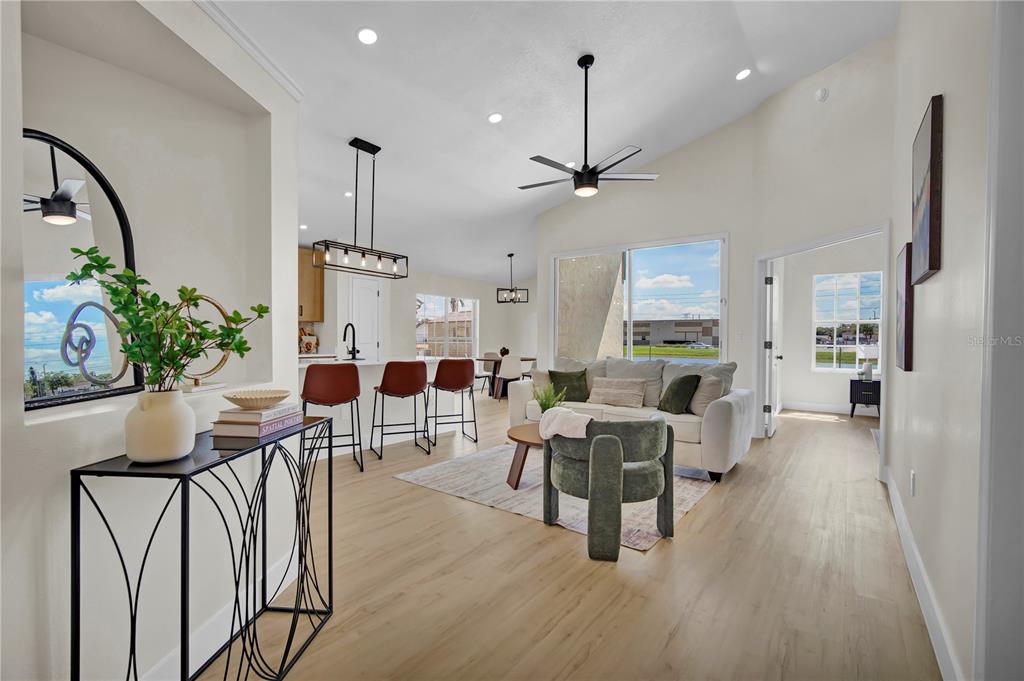 An open-concept living area features light wood flooring, a kitchen island, and a vaulted ceiling — 8320 SOUTHERN FOREST DRIVE, ORLANDO, FL