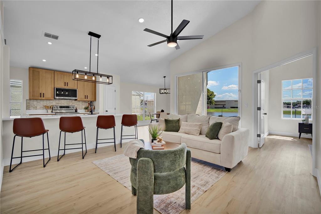 An open-concept living room and kitchen featuring light wood floors, a sofa, and bar seating — 8320 SOUTHERN FOREST DRIVE, ORLANDO, FL