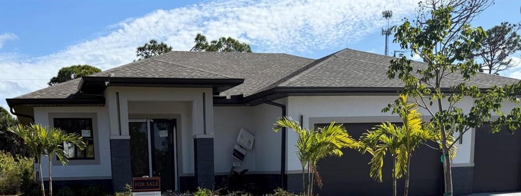 A modern single-story house with a gray shingled roof, white stucco walls, and dark accents — 47 BRIG CIRCLE E, PLACIDA, FL