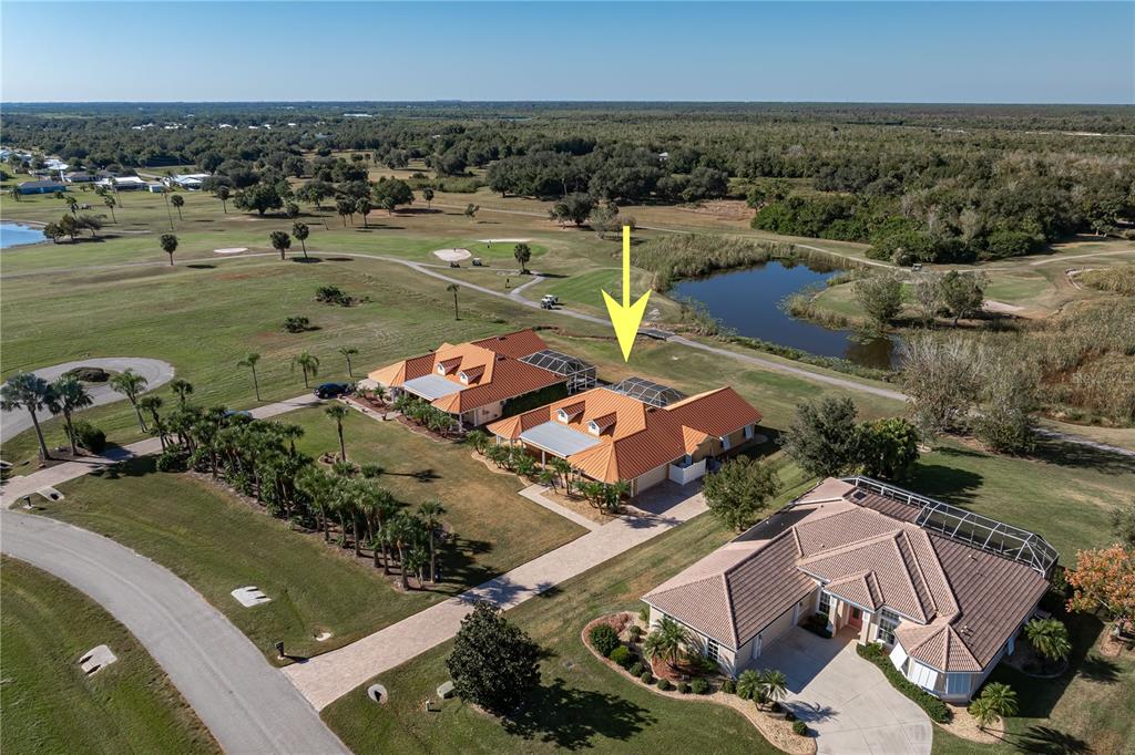 An aerial view shows three houses with orange tile roofs situated on a golf course — 8289 SW AVIARY ROAD, ARCADIA, FL