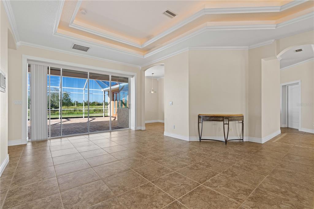 A spacious living room features tile flooring, a tray ceiling, and sliding glass doors to a patio — 8289 SW AVIARY ROAD, ARCADIA, FL