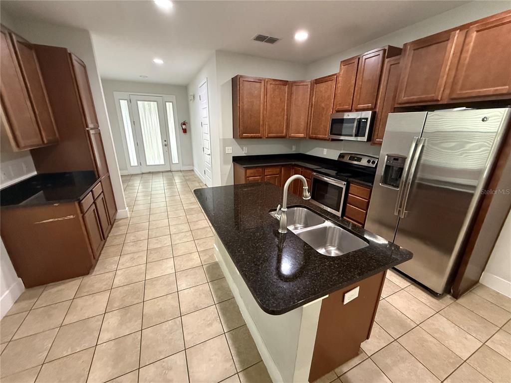 A kitchen with dark wood cabinets, stainless steel appliances, and an island with bar seating — 481 LASSO DRIVE, KISSIMMEE, FL