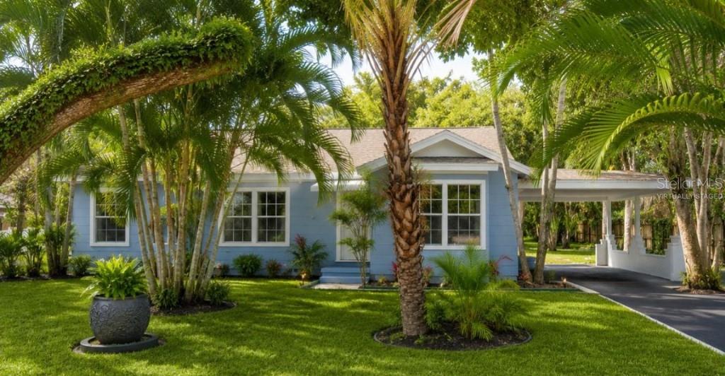 A light blue single-story house with a carport and palm trees in the front yard — 1714 2ND AVENUE E, BRADENTON, FL