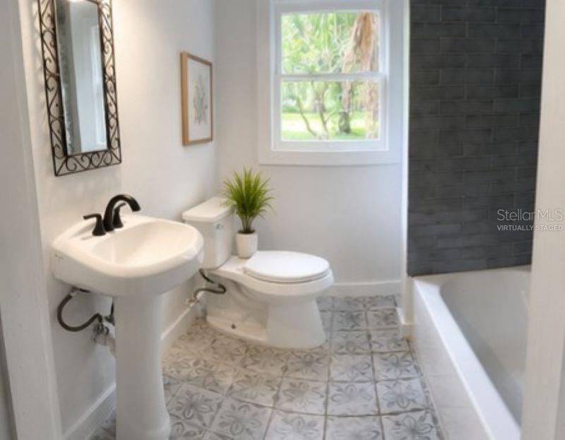 A bathroom features a pedestal sink, a toilet, a window, and a tiled bathtub surround — 1714 2ND AVENUE E, BRADENTON, FL