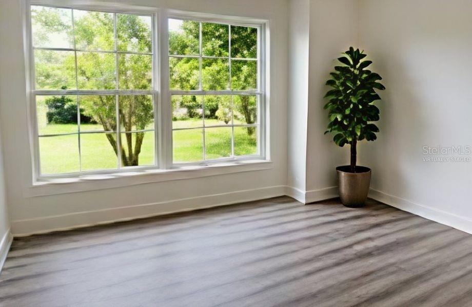 An empty room with light wood-look flooring, a large window, and a potted plant — 1714 2ND AVENUE E, BRADENTON, FL