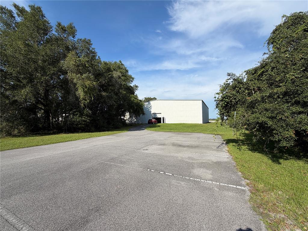 A large metal warehouse building sits at the end of an asphalt parking lot — 10601 SW 147TH CIRCLE, DUNNELLON, FL
