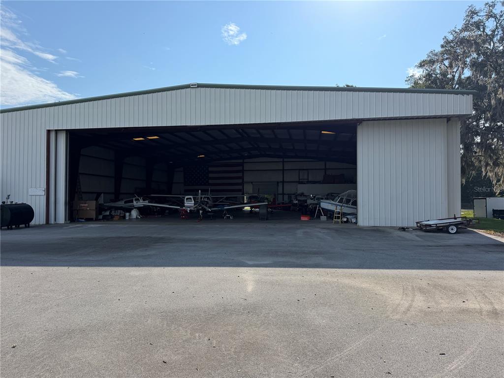 A large metal hangar with an open bay door houses several small airplanes and equipment — 10601 SW 147TH CIRCLE, DUNNELLON, FL