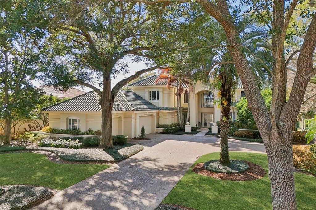 A two-story house with a tile roof, beige stucco exterior, and a paved circular driveway — 5145 LATROBE DRIVE, WINDERMERE, FL