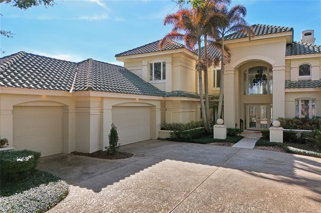 A two-story stucco house with a tile roof, three-car garage, and palm trees — 5145 LATROBE DRIVE, WINDERMERE, FL