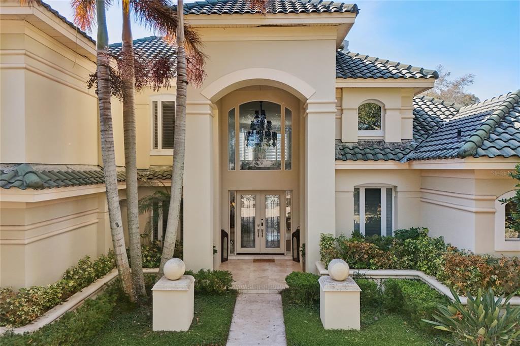 A two-story house exterior features a tiled roof, arched entryway, and a paved walkway — 5145 LATROBE DRIVE, WINDERMERE, FL