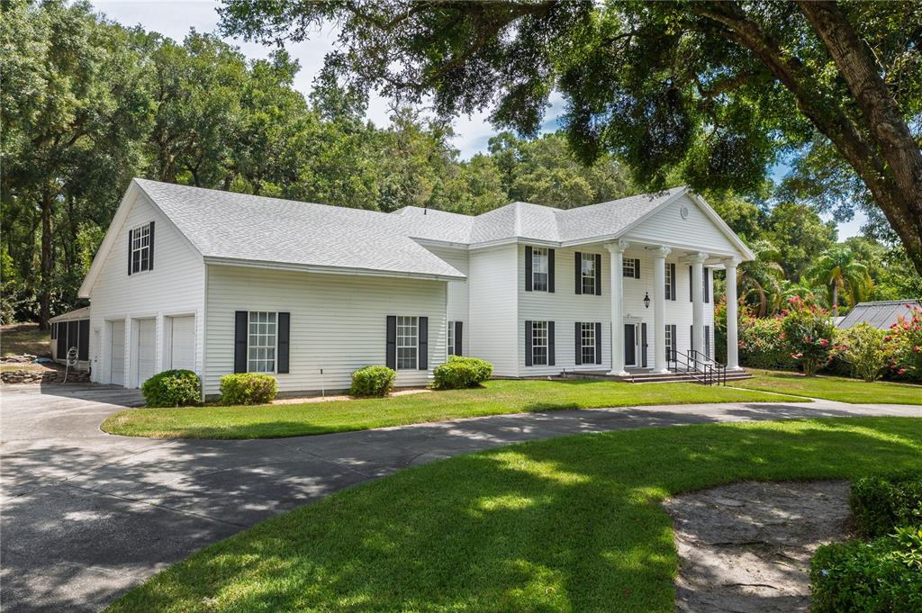 A two-story white colonial-style house with a columned porch and an attached garage — 7219 CHESTERHILL CIRCLE, MOUNT DORA, FL