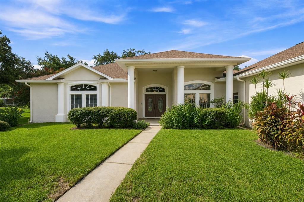 A single-story house with a columned entryway, double front doors, and a concrete walkway — 13750 DOWLING LANE, ODESSA, FL